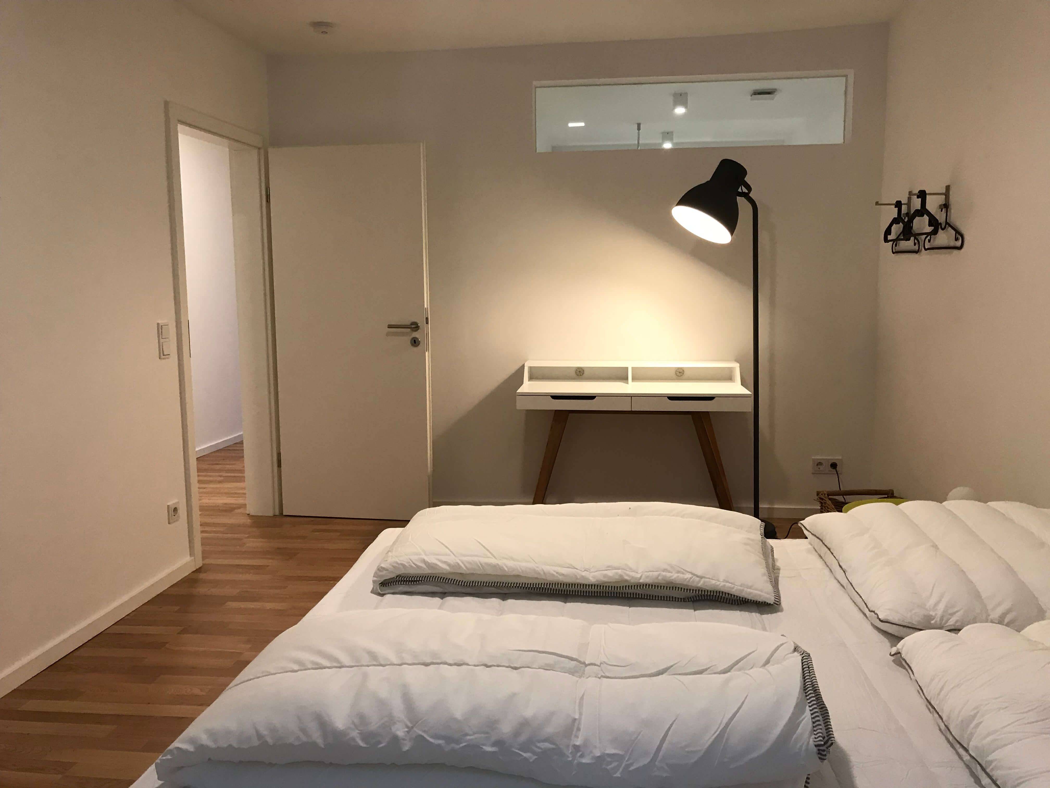 Blick ins Schlafzimmer mit Schreibtisch und Lampe vom Business Apartment im Weingut Schwaab. 