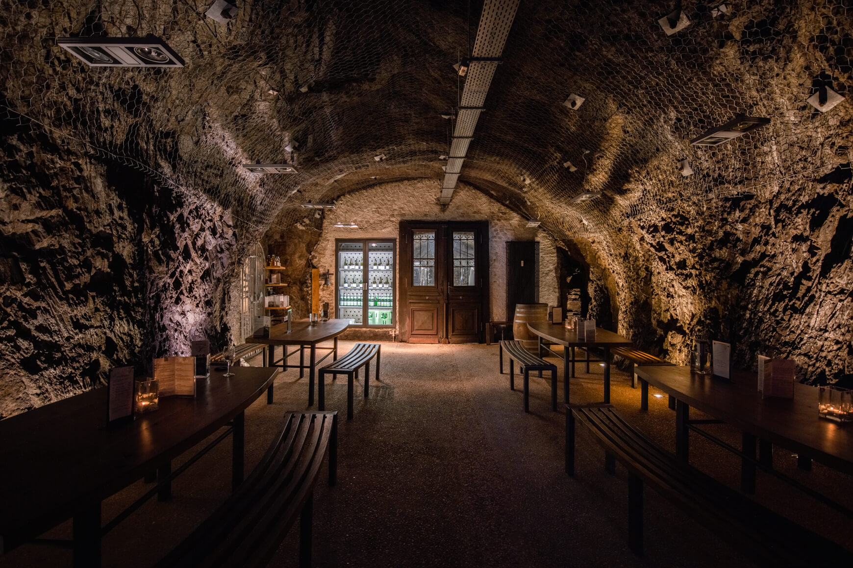 Blick in den Felsenkeller mit Tischen und Bänken und Beleuchtung während der Felsenkellertour 