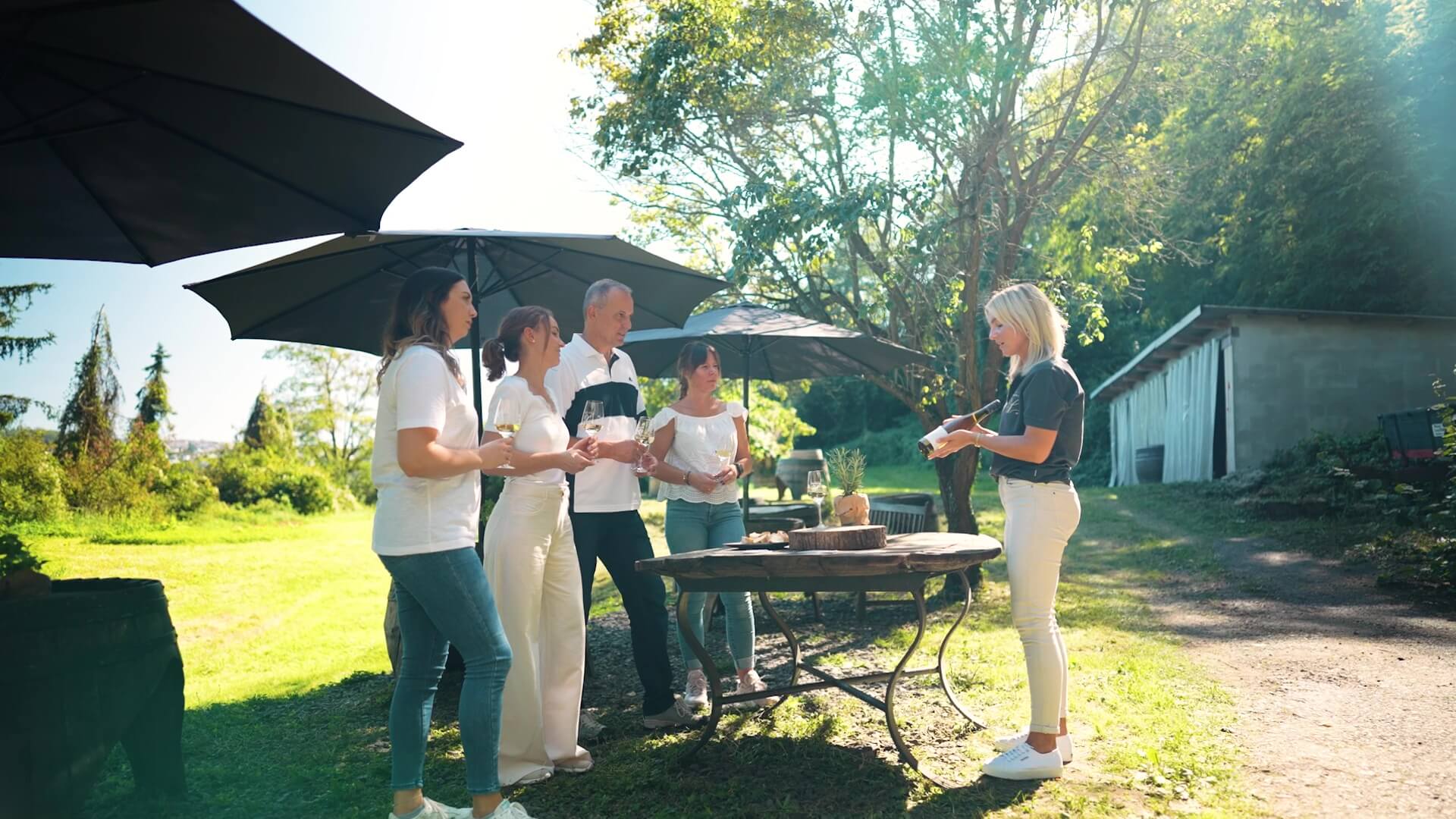 Weinverkostung an der Weinhütte während der Marienbergtour. Tourguide erklärt Wein an vier Gäste an der Weinhütte in der Marienbergtour im Koblenzer Marineberg im Weingut Schwaab.