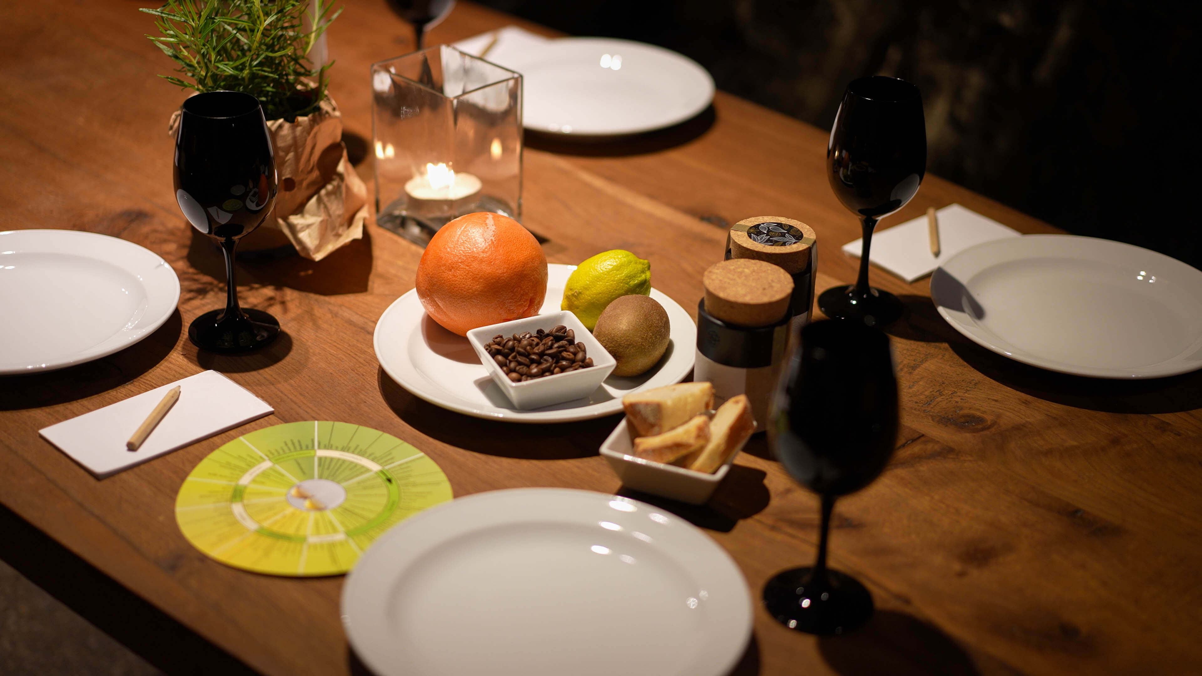 Eingedeckter Tisch der Weinwerkstatt Spurensuche nach Aromen im Keller vom Weingut Schwaab in Koblenz mit Tellern, Weingläsern, Obst, Aromen und Aromarad. 