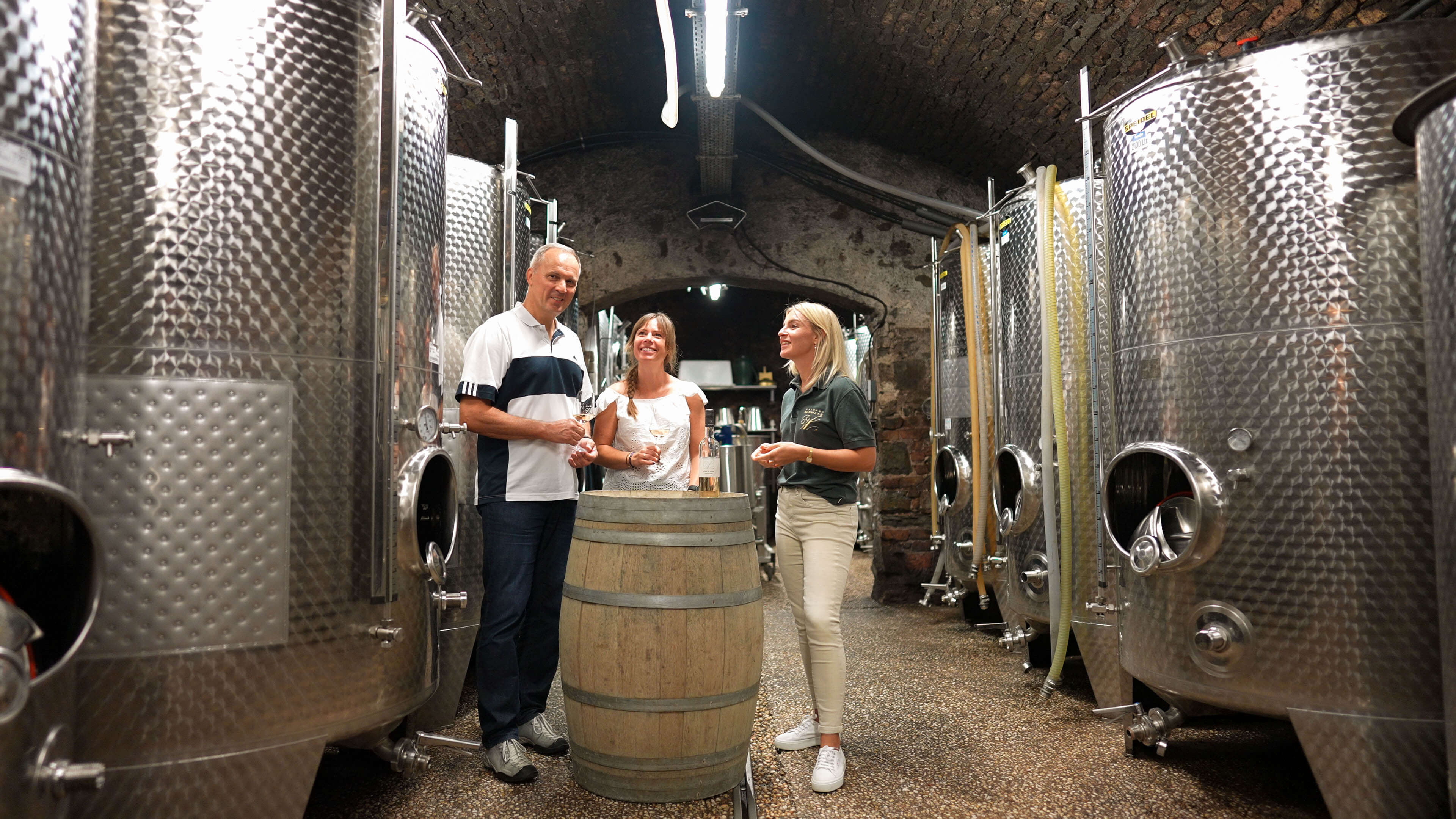 Zwei Gäste und Tourguide verkosten einen Wein im Tankkeller vom Weingut Schwaab in Koblenz während der Entdeckertour. 